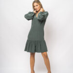 The girl wears a short green dress with long sleeves and a V-neckline.