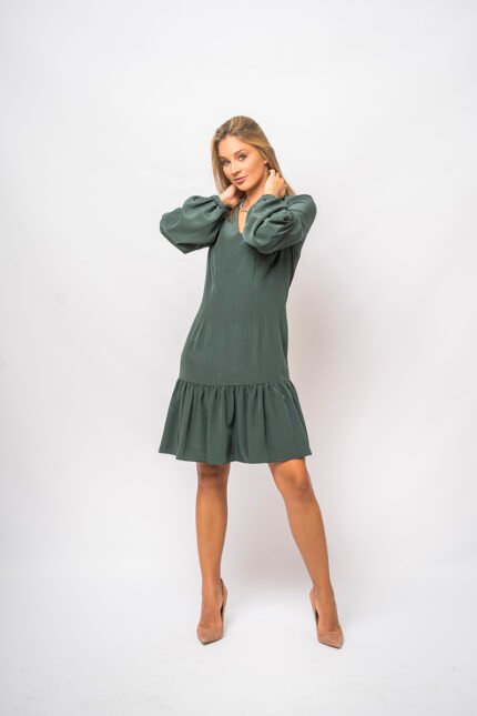 The girl wears a short green dress with long sleeves and a V-neckline.