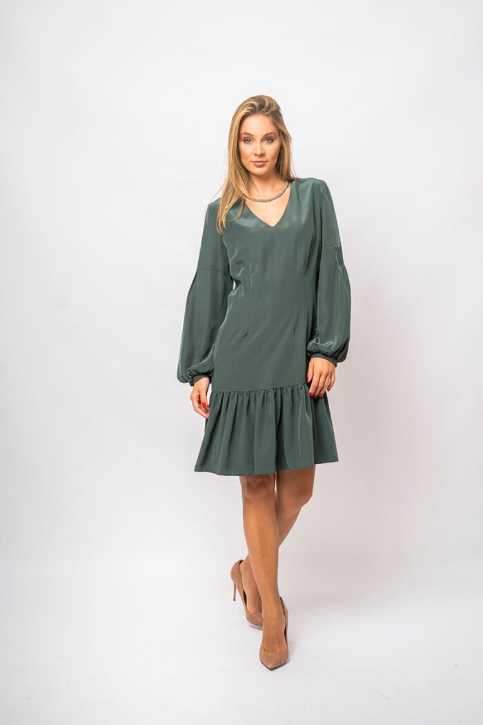 The girl wears a short green dress with long sleeves and a V-neckline.