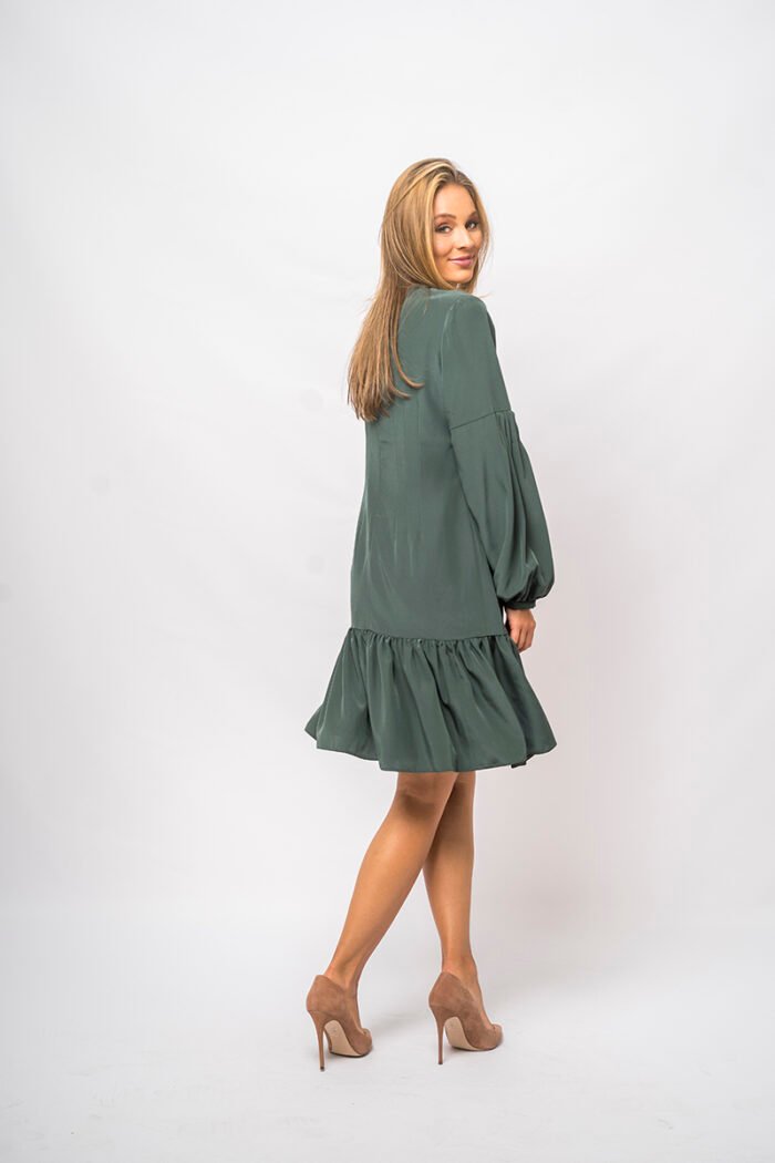 The girl wears a short green dress with long sleeves and a V-neckline.