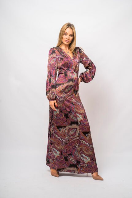 The girl wears a long purple patterned dress with long sleeves.