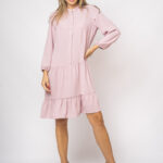 The girl wears a short pink dress with long sleeves.