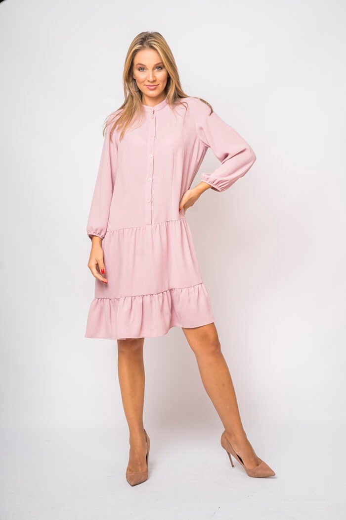 The girl wears a short pink dress with long sleeves.