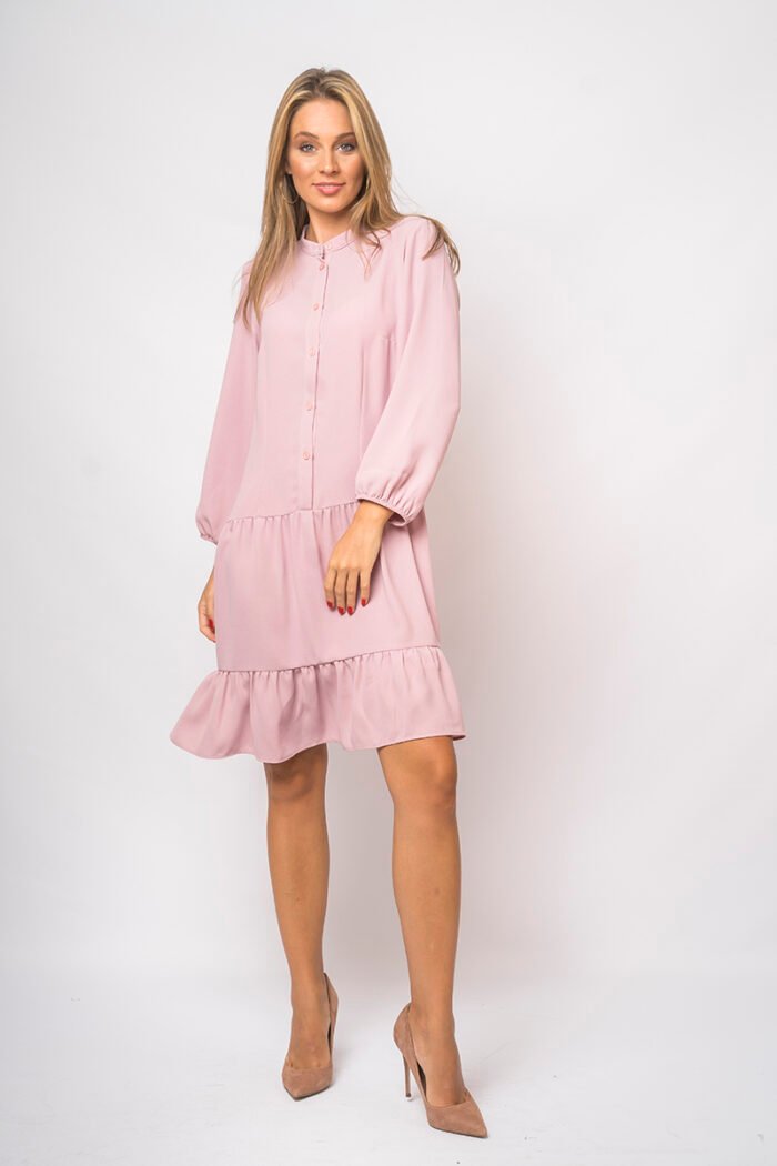 The girl wears a short pink dress with long sleeves.