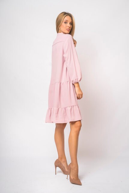 The girl wears a short pink dress with long sleeves.