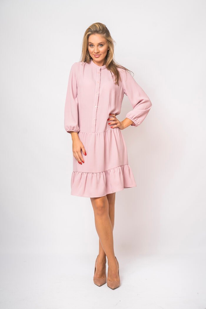 The girl wears a short pink dress with long sleeves.