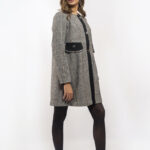 Devojka nosi sivo-beli dezenirani kaput.