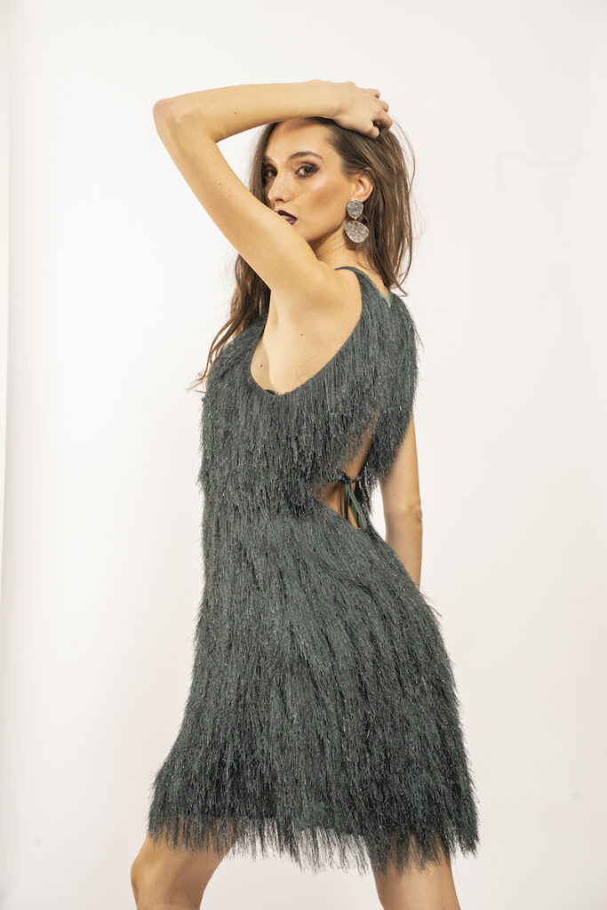 Devojka nosi kratku zelenu haljinu sa resama.