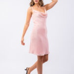 Devojka nosi kratku roze haljinu na bretele.