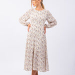 Devojka nosi cvetnu haljinu sa dugim rukavima.