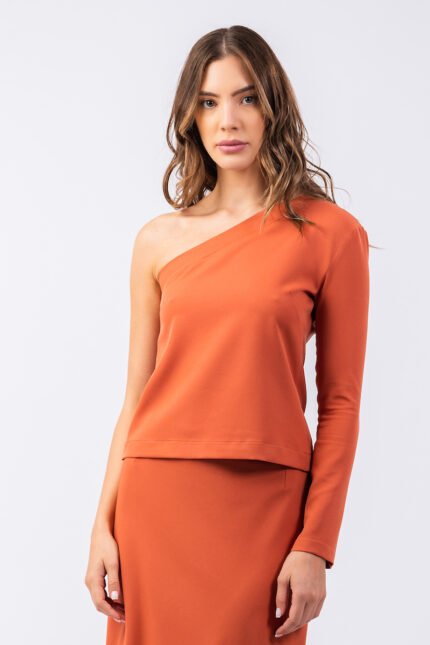 The girl wears an orange INKA top with an asymmetric cut on one shoulder.