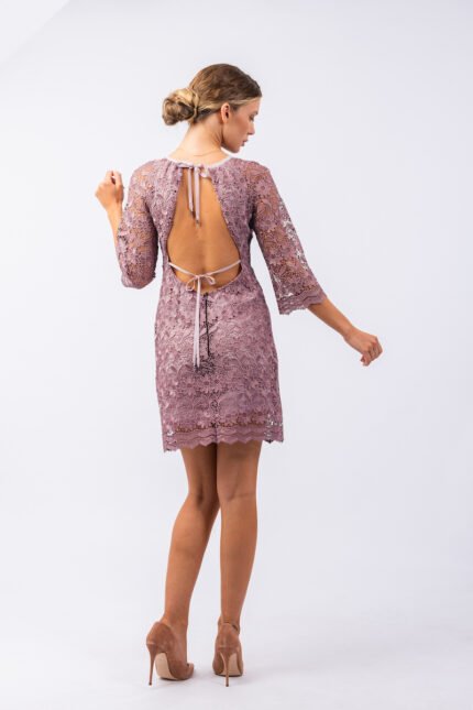 Blonde girl with tied hair wears HELENICA short purple lace dress with 3/4 sleeves and open back.