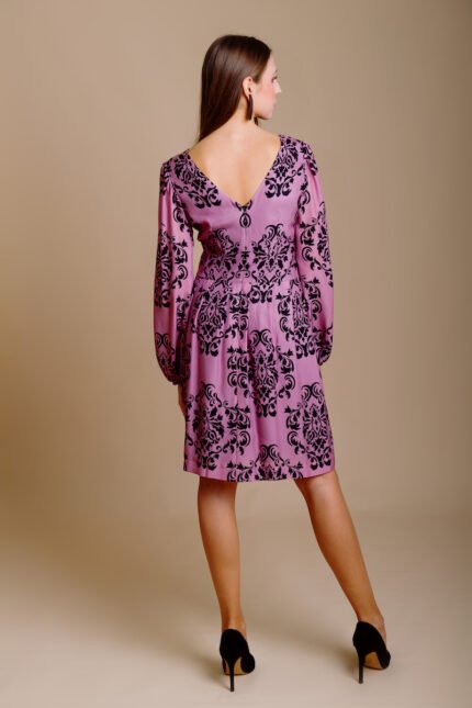 Girl wears short MARIA dress crafted from patterned silk in luxurious shade of purple with black floral details.