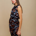 Devojka nosi dugu svilenu MIRNA haljinu tigrastog printa ispred bež pozadine.