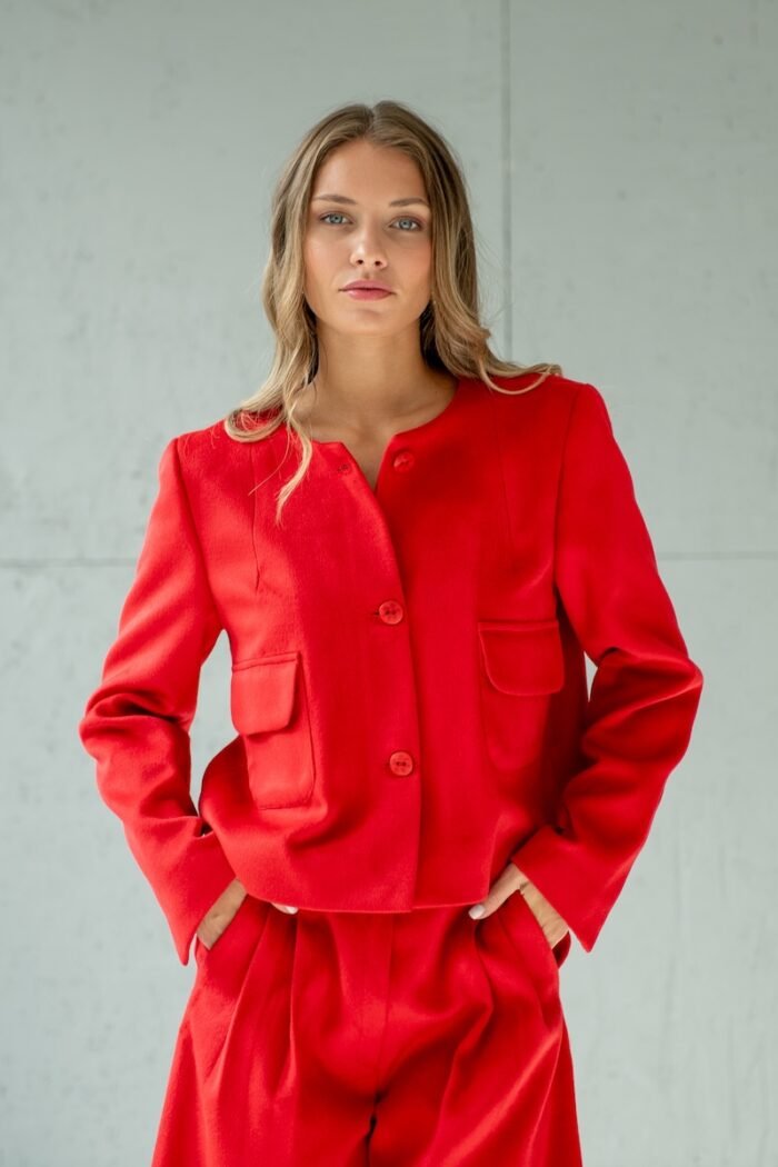 Girl wears short RUBY jacket made from red material with flap pockets.