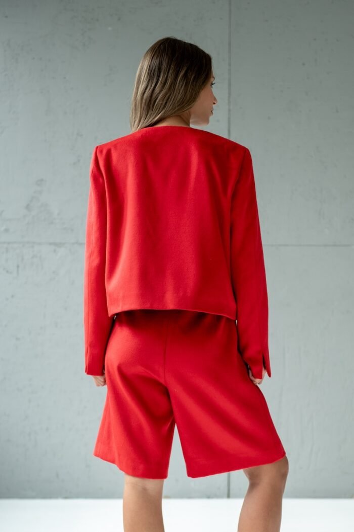 Girl wears short RUBY jacket made from red material with flap pockets.