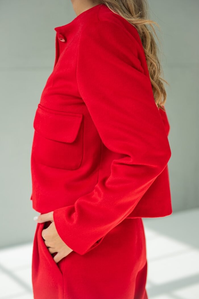 Girl wears short RUBY jacket made from red material with flap pockets.