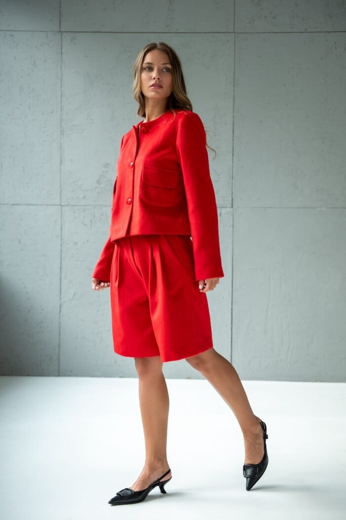 Girl wears short RUBY jacket made from red material with flap pockets.