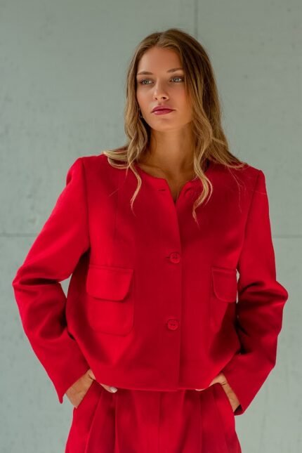 Girl wears short RUBY jacket made from red material with flap pockets.