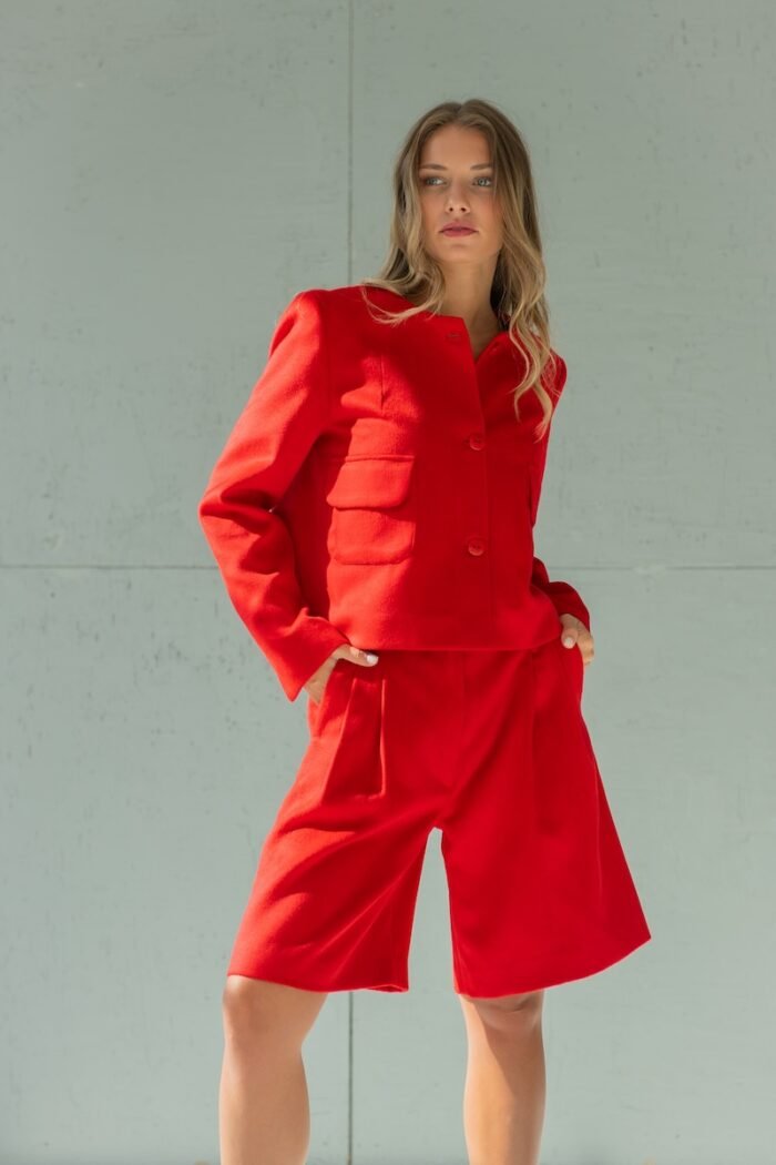 Girl wears short RUBY jacket made from red material with flap pockets.