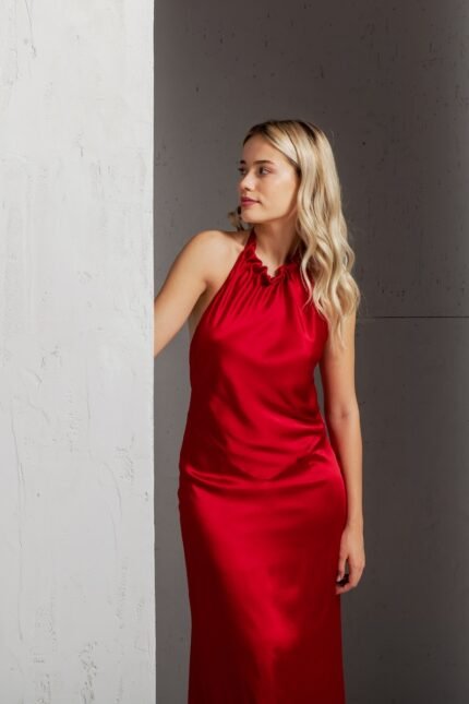 The blonde girl wears a long SIENA dress in dark red satin silk with an open back.