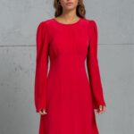 Devojka nosi kratku crvenu TEONA haljinu od svile sa dugim rukavima.