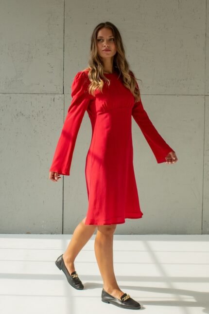 The girl is wearing a short red TEONA silk dress with long sleeves.