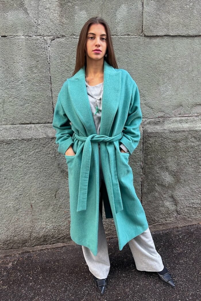 Girl wears tie-waist coat made of soft wool blend in an authentic shade of green.