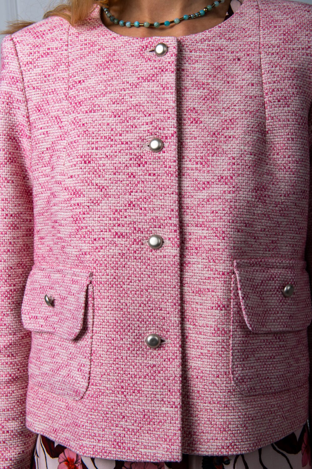 The woman wears a pink cotton blazer.