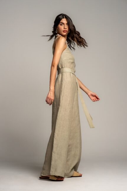 The girl wears a beige linen jumpsuit with wide legs.