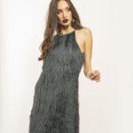 Devojka nosi kratku zelenu haljinu sa resama.