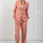 The girl is wearing a peach blazer and pants set.