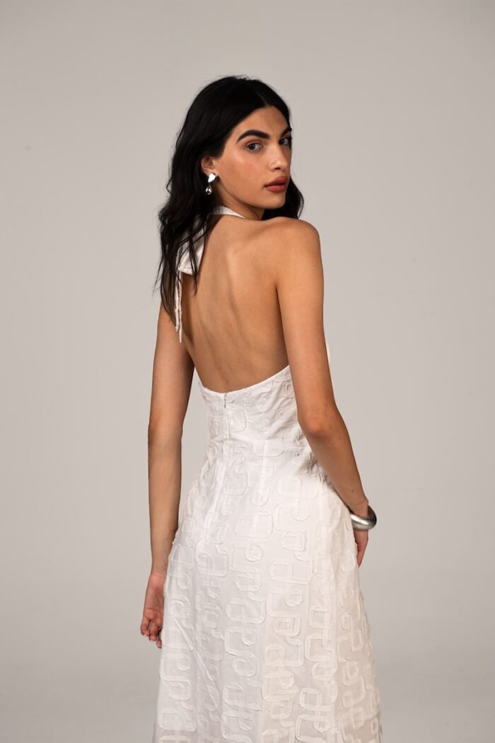 The girl wears a long white dress with an open back.