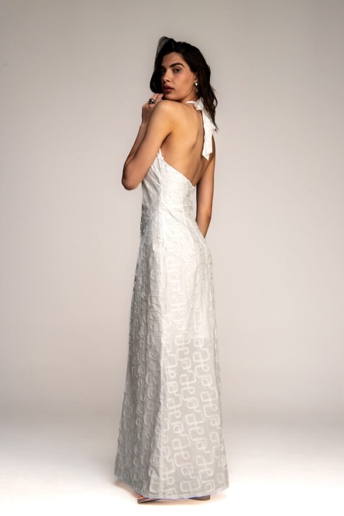 The girl wears a long white dress with an open back.