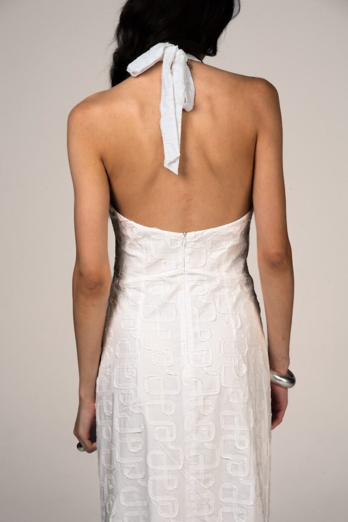 The girl wears a long white dress with an open back.