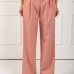 Devojka nosi široke pantalone u boji breskve i belu majicu na bretele.