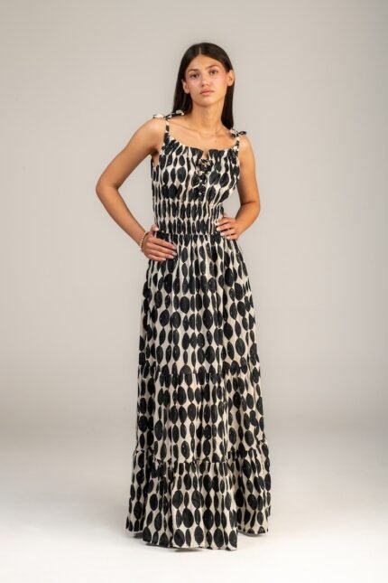 The girl wears a maxi, black and white dress with straps.