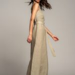 ISLA kombinezon od laganog lana u bež boji, sa tankim bretelama, pojasom za vezivanje u struku i širokim nogavicama.