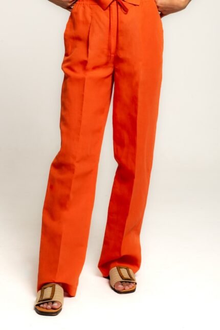 The girl is wearing an orange vest and pant set.