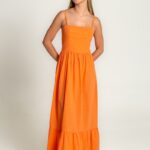 The girl is wearing a midi orange dress with straps.