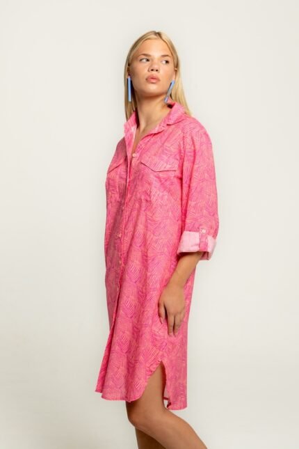 The girl wears a midi shirt-dress in a pink pattern.