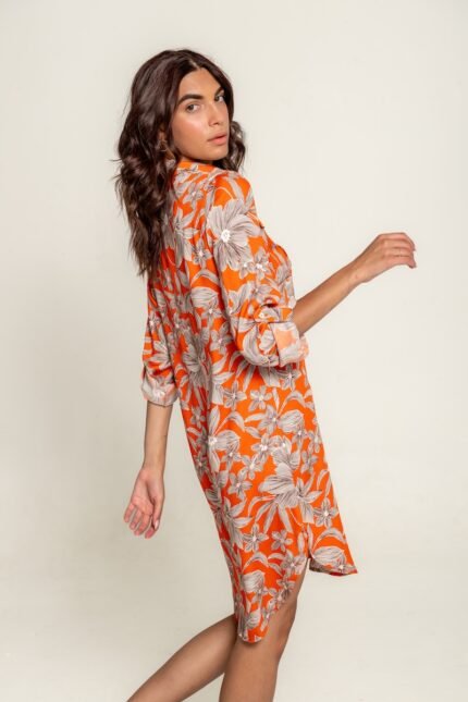 The girl wears an orange midi shirt-dress with a floral pattern.