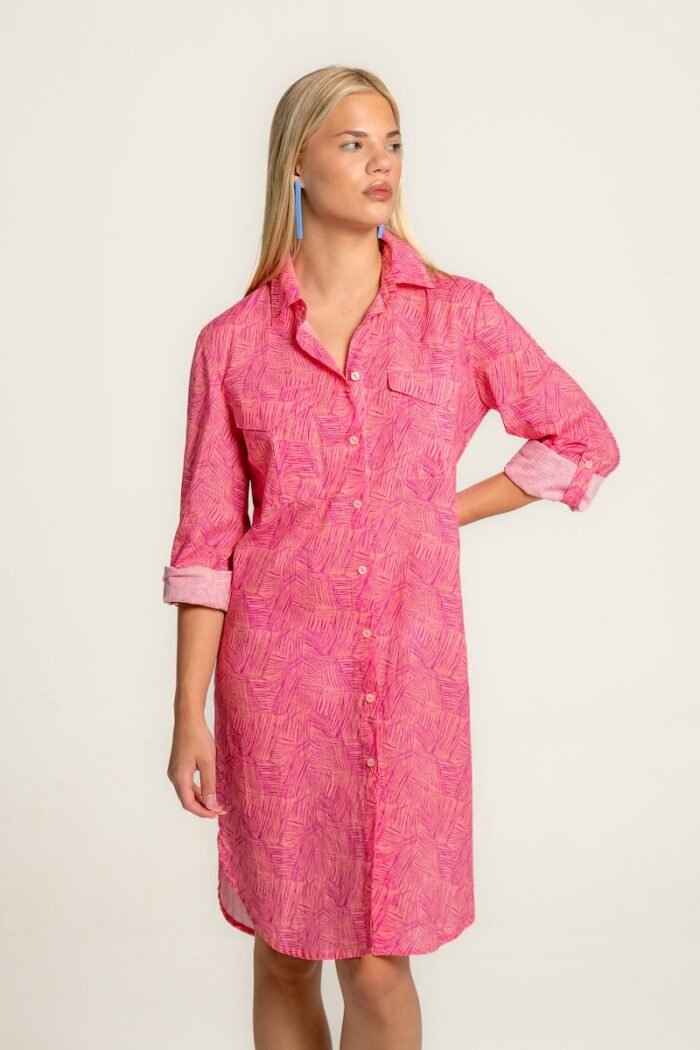 The girl wears a midi shirt-dress in a pink pattern.