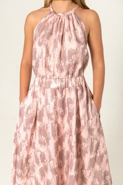 The girl is wearing a patterned pink print sleeveless dress.