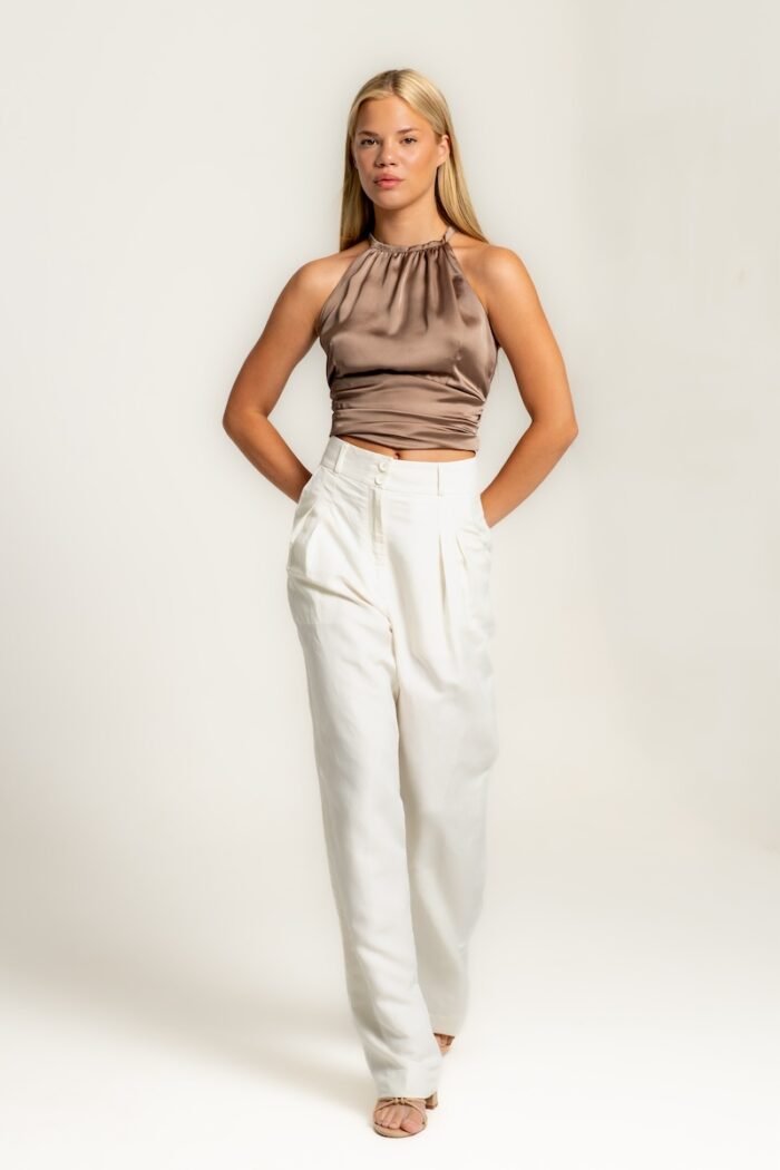 The girl wears white wide leg pants and a satin brown sleeveless top.