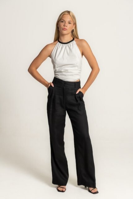 The girl wears black linen wide leg pants and a white sleeveless top with dots.