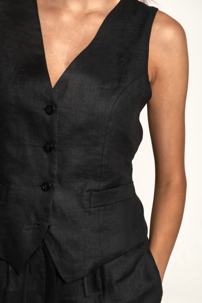 The girl wears a black linen vest and black pants.