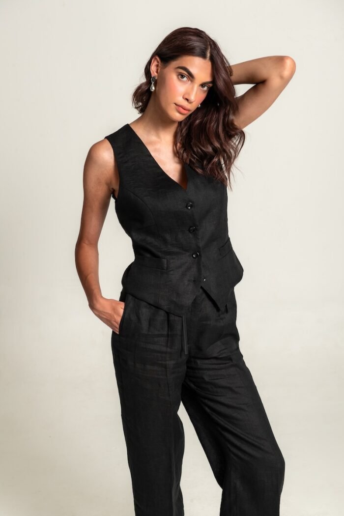 The girl wears a black linen vest and black pants.