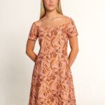 Braon-šarena haljina sa kratkim rukavima i otvorenim ramenima, ukrašena apstraktnim listastim printom u toplim nijansama.