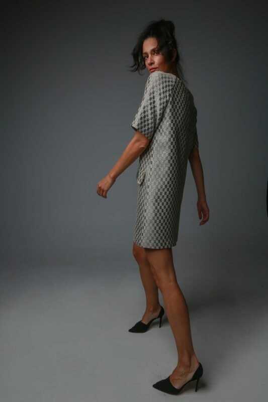 The woman wears a short-sleeved dress with a geometric pattern.